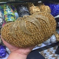 Close-up of golden rhinestone evening clutch with butterfly clasp and wavy crystal texture - Gold / Gold Rhinestone