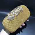 Close-up of a golden evening clutch featuring sparkling crystals and a leaf-shaped clasp - Gold Rhinestone Gold Flower