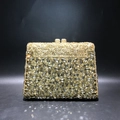 Macro detail of luxury golden evening bag with grey teardrop rhinestones and hollow metalwork - Gold