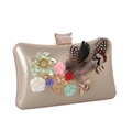 Detail of evening clutch featuring 3D resin flowers, feathers, and a jeweled bee ornament - Gold