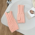 Detalle de mitones de punto rosa con diseño de trenzas y textura suave sobre mesa blanca - Coral