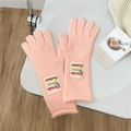 Detail of warm pink knitted five-finger gloves with a stylish brand label on the wrist - One Size / Coral