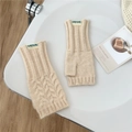 Close-up of beige cable knit fingerless gloves with Doria Dore brand label on a table - Off White