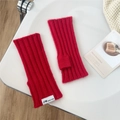 Rote Strick-Armstulpen mit JW-Logo-Etikett auf weichem minimalistischem Hintergrund - Rot