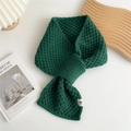 Detalle de bufanda de punto de gofre verde oscuro con etiqueta en mesa minimalista - Verde