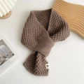 Detail of a brown waffle knit scarf with a white embroidered label on a cozy wooden tray - Coffee