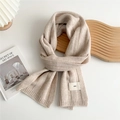 Detail of oatmeal knit scarf showing vertical stripe texture and minimalist emo label - Off White