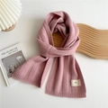 Detail of pink knitted scarf with ribbed texture and white woven label on white background - Pink