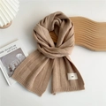 Detail of oatmeal knit scarf featuring vertical ribbed texture and a minimalist 'emo' label - Oatmeal