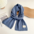 Close-up of navy blue knit scarf with vertical ribbed texture and minimalist emo tag - Blue