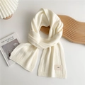 Close-up of beige knitted scarf featuring vertical stripes and a minimalist emo fabric tag - Cream