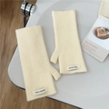 Detalle de guantes de punto crema sin dedos con una etiqueta tejida en la muñeca - Talla única / crema