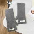 Gros plan de mitaines en maille côtelée grise avec étiquette tissée sur surface blanche - Taille unique / Gris