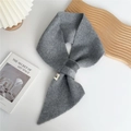 Detail of grey knitted cross scarf texture with small white woven label on white surface - 14x92cm / Gray
