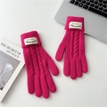 Close-up of bright pink cable knit gloves with a stylish fold-over cuff and fabric label - Rose Red