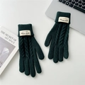 Detail of dark green cable knit gloves with ribbed cuffs on a white desk workspace - Dark Green
