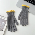 Détail de gants en tricot gris avec volants jaunes et bouton en métal sur un bureau blanc - Gris Contraste Bordure Ondulée