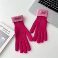 Close-up of pink knitted gloves with fuzzy sheepskin cuffs and brand label on desk - One Size / Rose Red