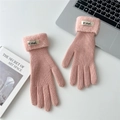 Detail of pink knitted gloves with white faux fur cuffs and brand label on a desk - One Size / Light Pink