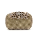 Detailed macro view of the rhinestone-studded leaf buckle on the gold evening clutch bag - Gold