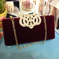 Détail de la pochette de soirée en velours rouge avec boucle couronne en strass dorés et chaîne - Bordeaux