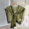 Detail van een geknoopte gebreide sjaal met groen en taupe contrastrand en het merklabel - Groen Met Grijze Rand