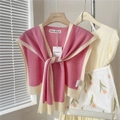 Detail van een roze en beige gebreide sjaal met striksluiting op een houten hanger - Roze Met Beige Rand