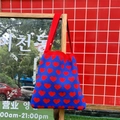 Detail of blue knit tote bag with red heart jacquard pattern hanging on wooden stand - Blue Heart Pattern