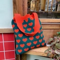 Detail of dark green knit tote bag with orange heart pattern on thick textured fabric - Orange Green Heart Pattern
