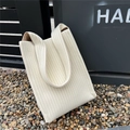 Close-up of cream-colored knit tote bag showing vertical ribbed texture and soft fabric - Beige