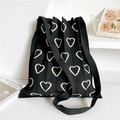 Close-up of black knitted shoulder bag with cream heart jacquard and pleated texture - Black Hollow Heart