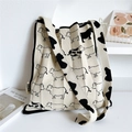Close-up of cream knit tote bag featuring cow print pattern and woven HSM brand label - Cow Print