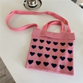 Detailansicht der rosa gestrickten Tragetasche mit Herzmuster auf weißem Tisch - Herz Rosa