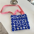 Detail der blau-weißen Stricktasche mit rosa gewebten Riemen auf einer weißen Oberfläche - Halbkreis Blau