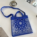 Blue knitted tote bag with white paisley pattern showing texture and shoulder strap detail - Paisley Blue