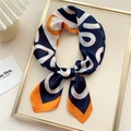Elegant silk scarf featuring navy blue and orange geometric prints tied in a bow - Bold Line Orange Navy