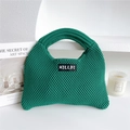 Primer plano de bolso tote de punto verde esmeralda con textura de punto y etiqueta - verde oscuro