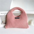 Detail of pink knitted tote bag showing thick crochet texture and black woven brand label - Pink