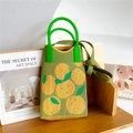 Detail of green knit crossbody bag with orange patterns and lime green ring handles - Green Fruit