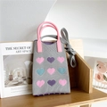 Detail of grey knitted bag with heart jacquard pattern and pink round handle on bookshelf - Grey Heart