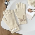 Detail der cremefarbenen Strickhandschuhe mit Schleife und Touchscreen-Funktion - Gebrochenes Weiß