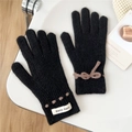 Nahaufnahme von schwarzen Strickhandschuhen mit brauner Schleife und Webetikett im Winterstil - Schwarz