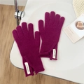 Close-up of magenta pink wool knitted gloves with stylish brand label on white table - One Size / Rose Purple