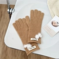 Detail of warm camel knit gloves featuring cute white pom-poms and brand label on wrist - One Size / Camel