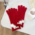 Detail of red knit gloves featuring soft white pom-poms and ribbed cuffs on a white tray - One Size / Red