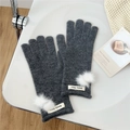 Close-up of dark grey knitted gloves featuring soft white pom-poms and brand label detail - One Size / Dark Gray