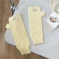 Detalle de mitones de punto amarillo claro mostrando el canalé y la etiqueta tejida decorativa - Beige