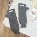 Detail of grey knitted fingerless gloves with Jennie Wool label on white background - One Size / Knit Patch Style / Gray