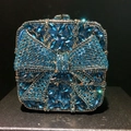 Detail of blue rhinestone evening clutch showing intricate crystal bow pattern - Teal