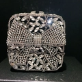 Close-up of a silver bow evening clutch featuring intricate crystal diamond flower patterns - Black